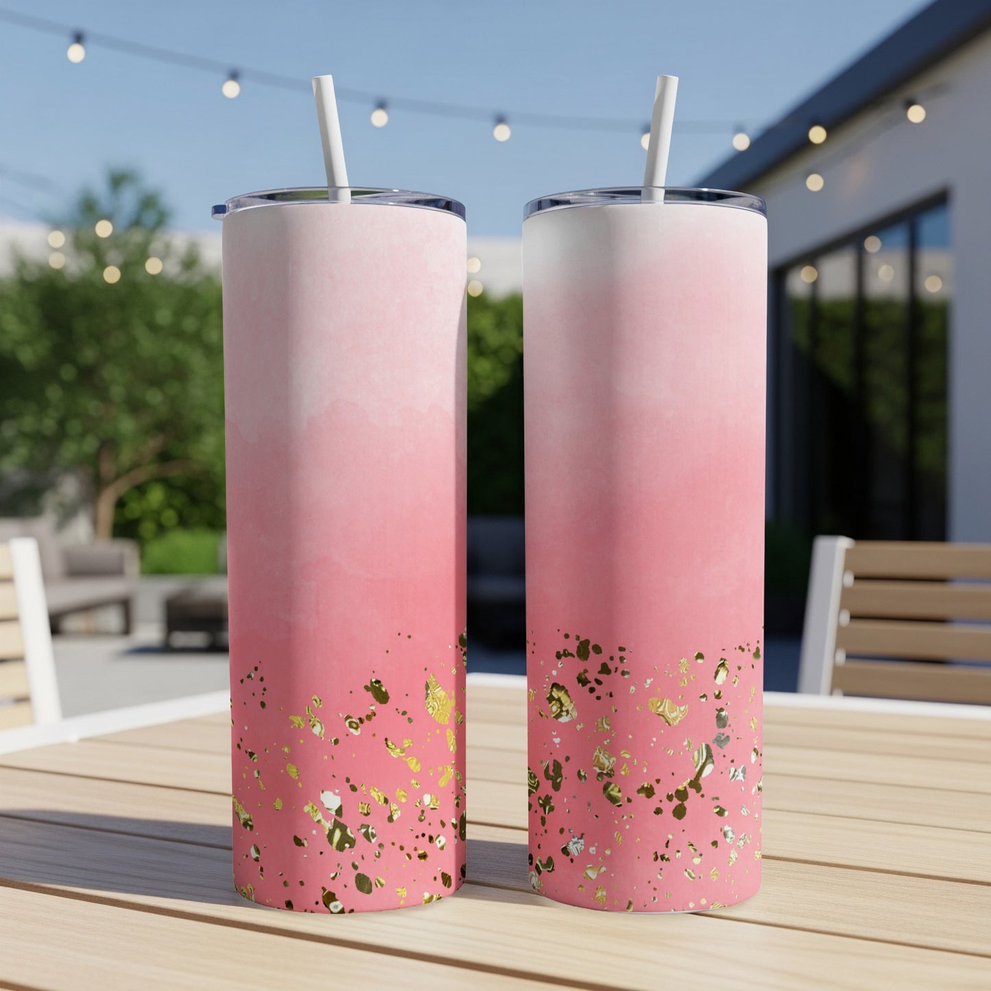 Two pink ombre tumblers with gold glitter accents and straws on a table.
