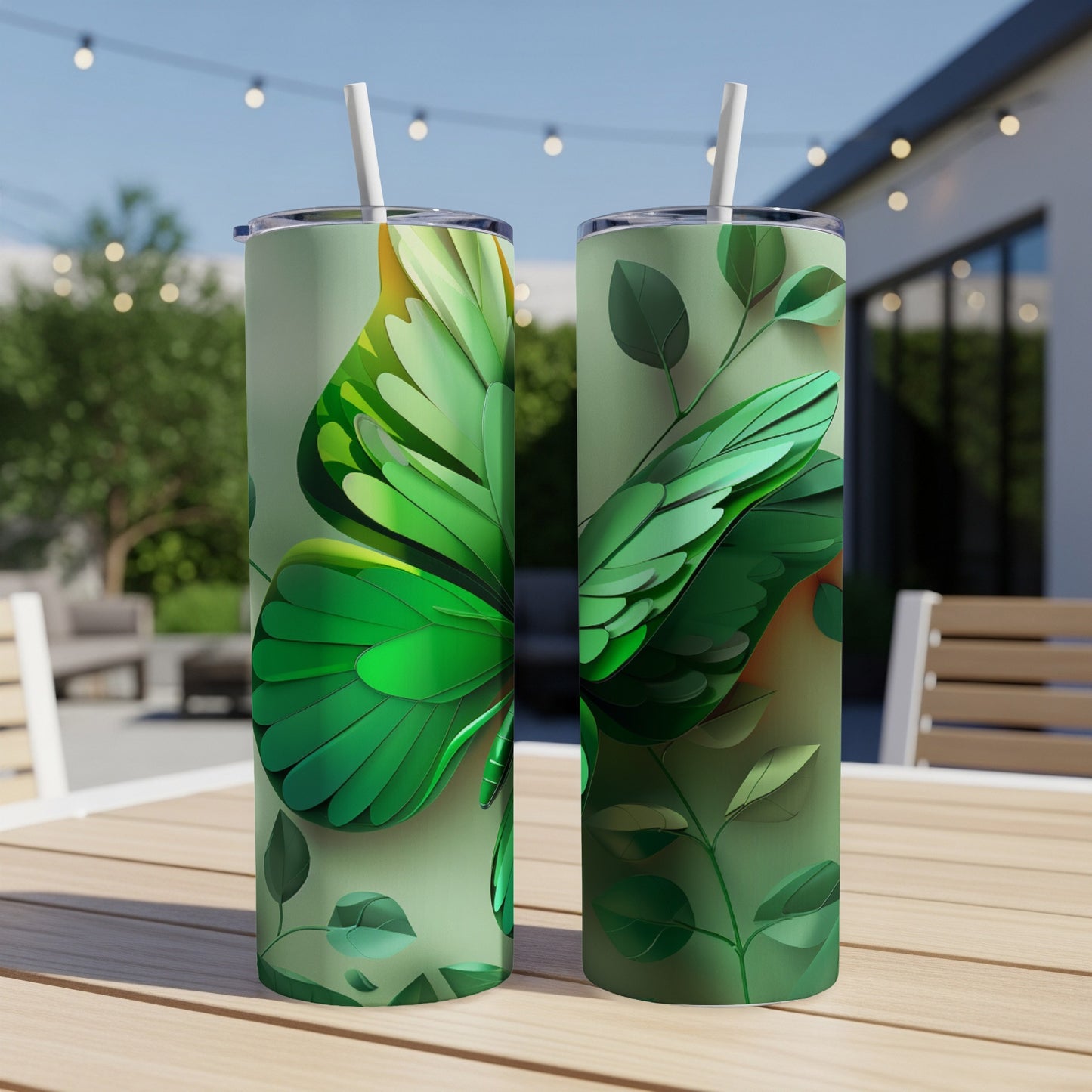Green butterfly wing pattern on two tumblers with straws on a table.