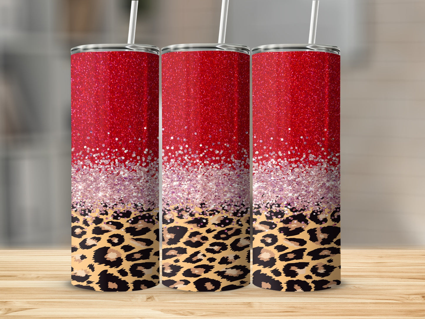Three red glitter tumblers with leopard print design on a wooden surface.
