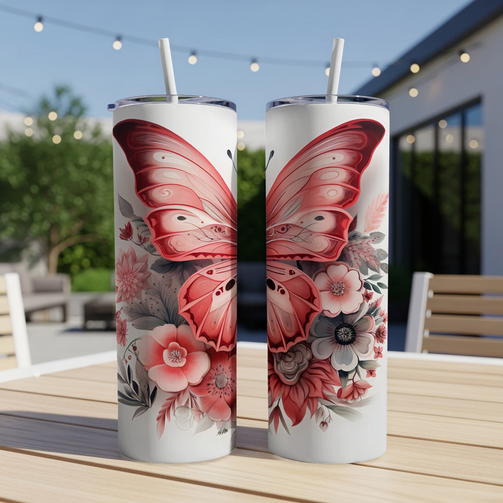 Two tumblers with pink butterfly and floral designs on a wooden table.