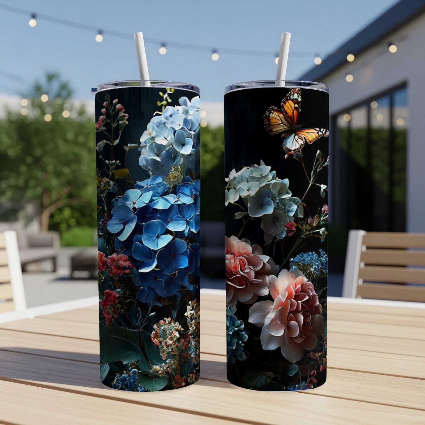 Two tumblers with floral and butterfly designs, displayed outdoors on a table.