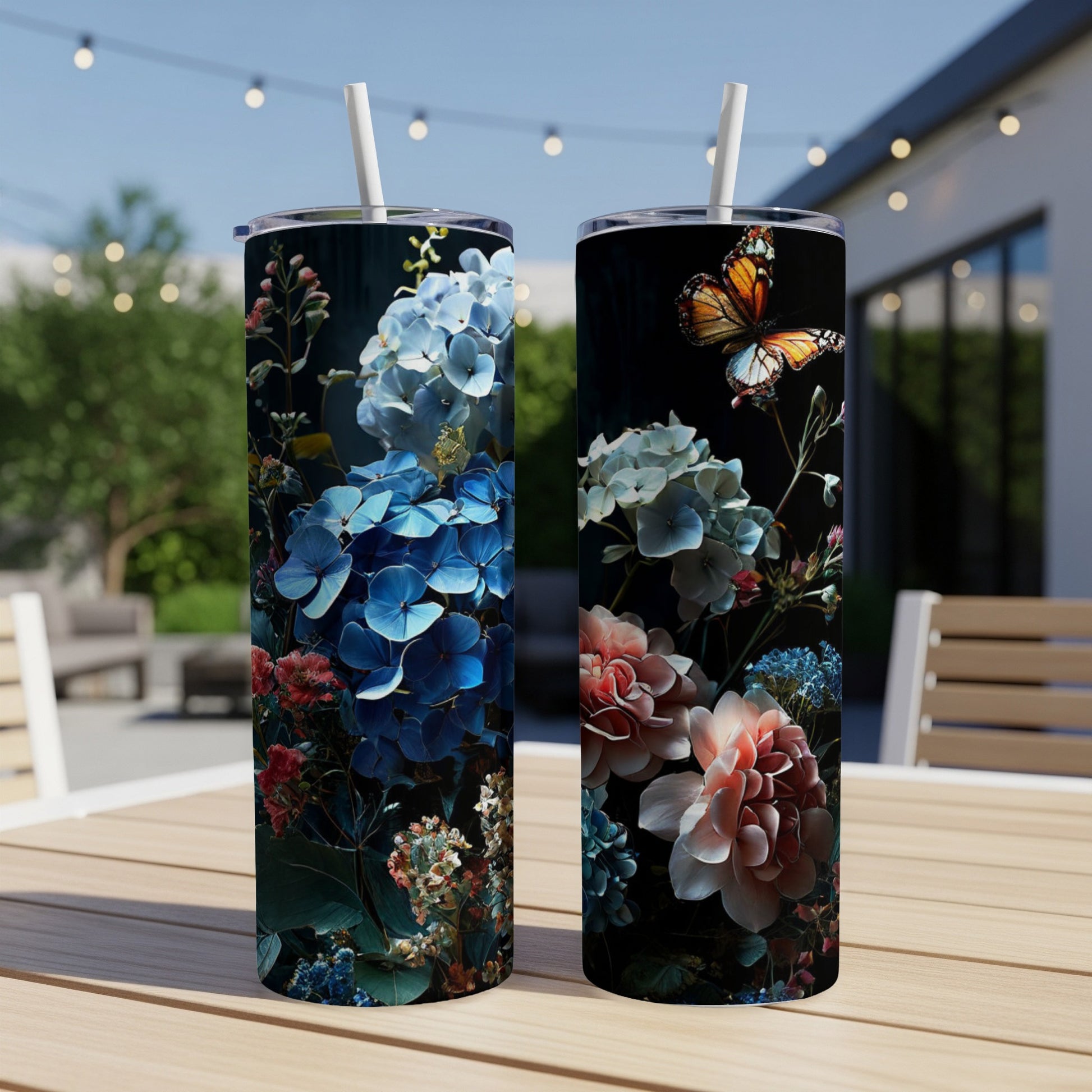 Two tumblers with floral and butterfly designs, displayed outdoors on a table.