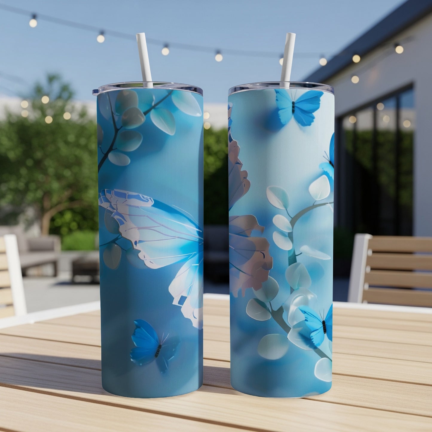 Two blue tumblers with white butterfly and leaf patterns on a table.