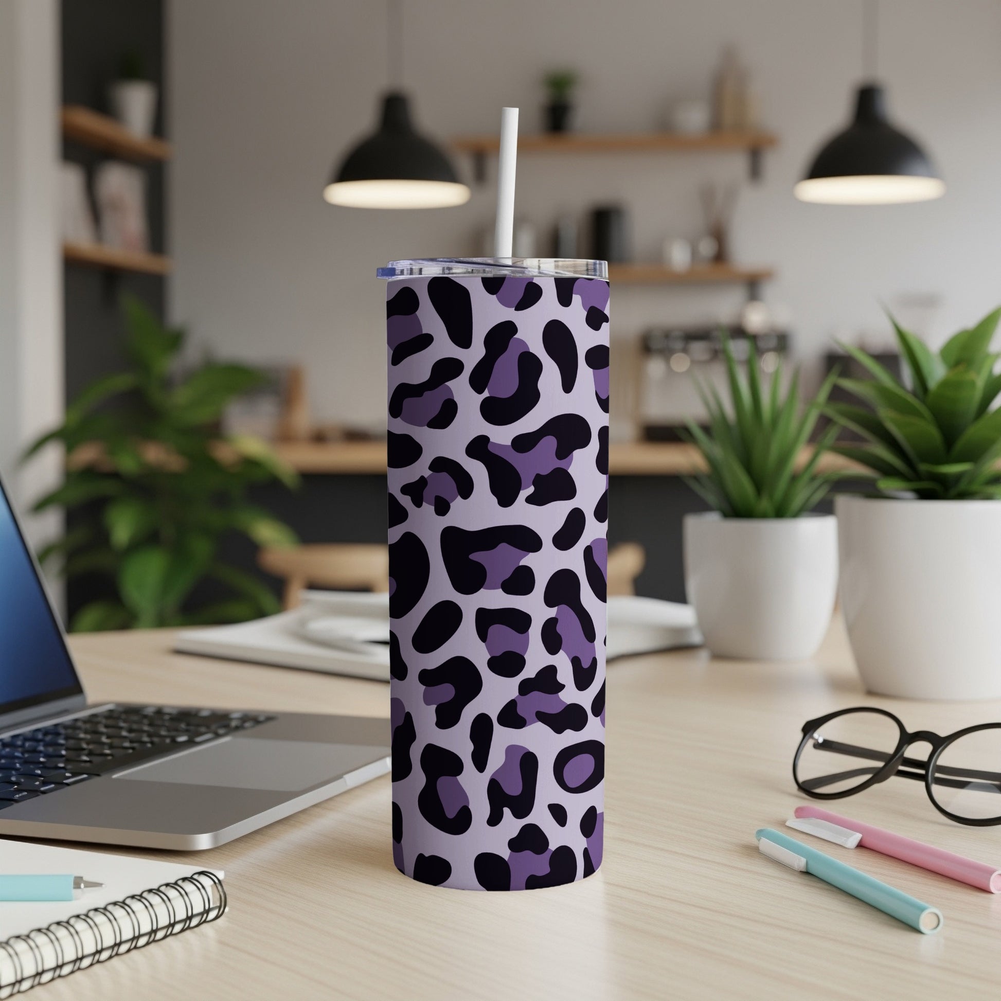 Purple leopard print tumbler with straw on a desk next to a laptop.