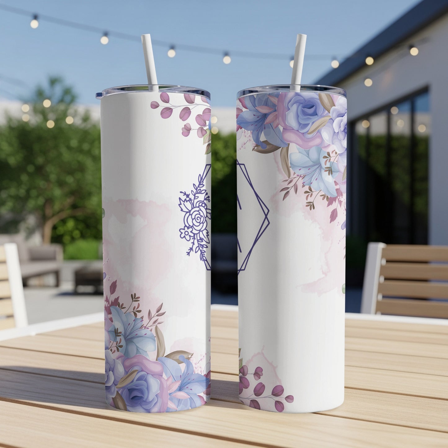 Two white tumblers with floral and geometric designs, displayed outdoors.