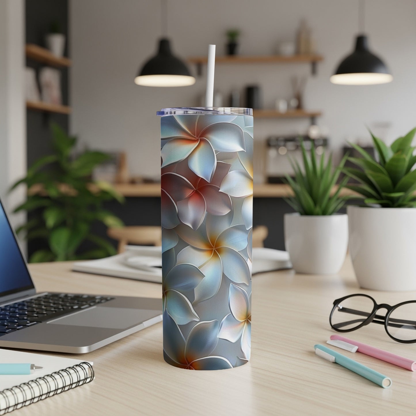 Silver tumbler with blue and red floral pattern on a desk.