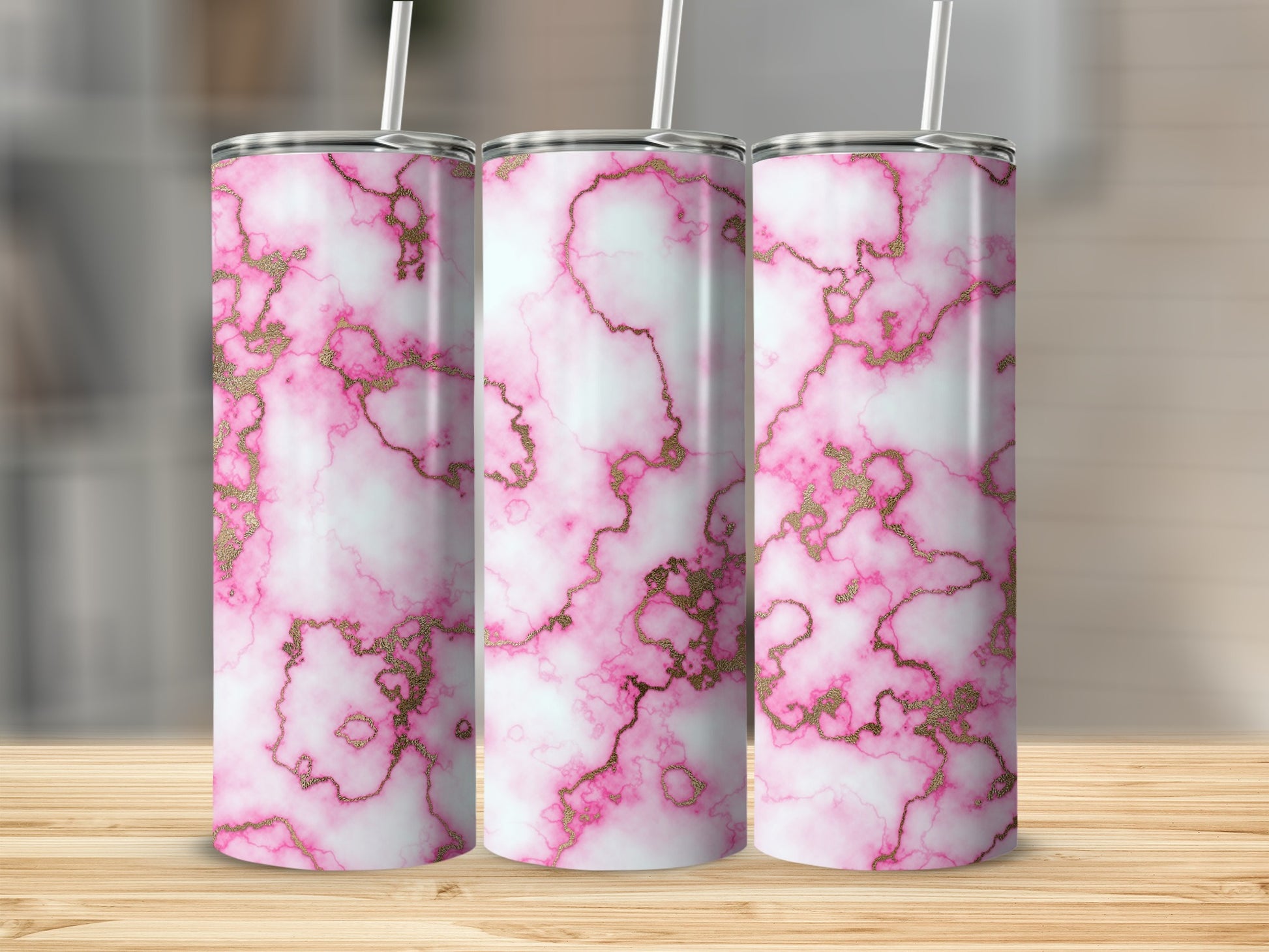 Three pink marble tumblers with gold veining and straws on a wooden surface.