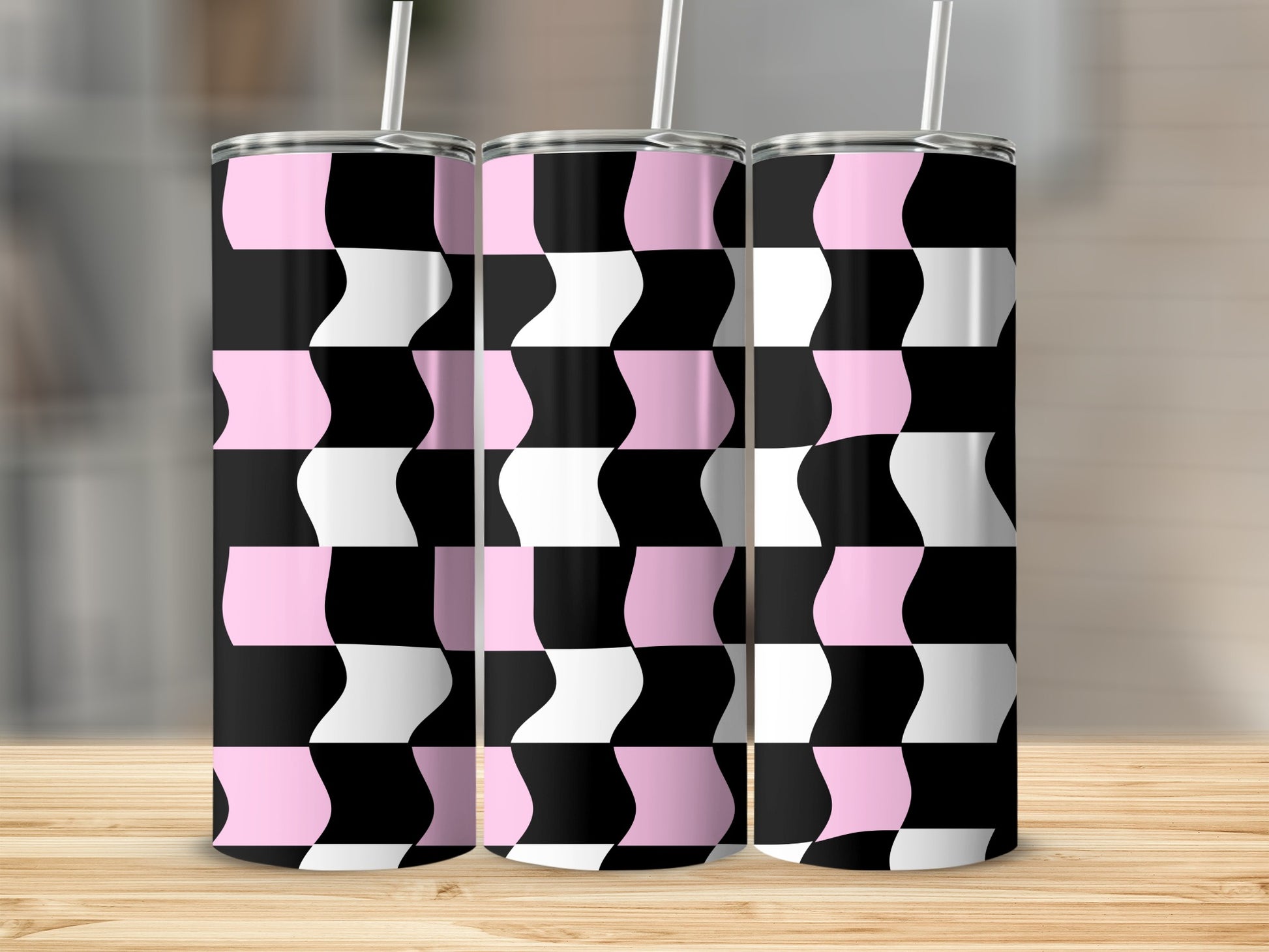 Three pink and black checkered tumblers with straws on a wooden surface.