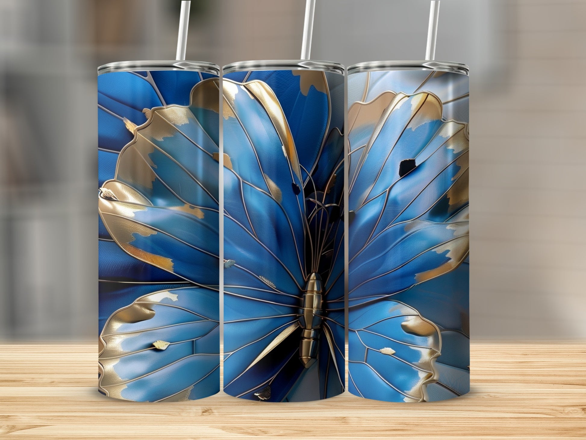 Three blue butterfly tumblers with gold accents on a wooden surface.
