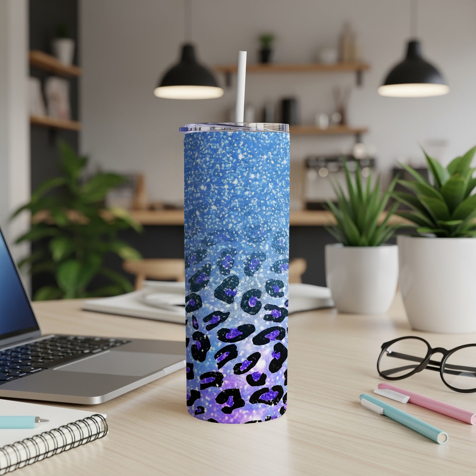 Blue glitter tumbler with purple leopard print on a desk.