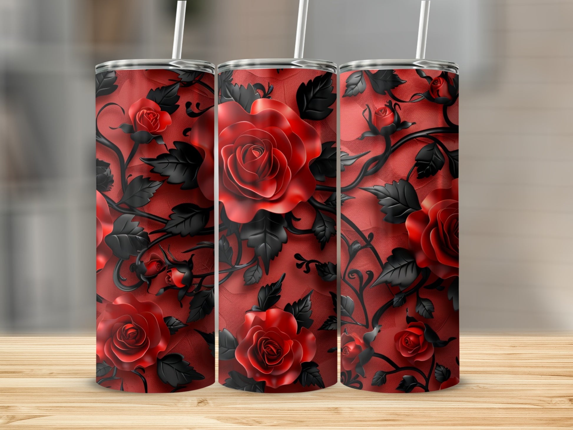 Three tumblers with a red rose and black vine pattern on a wooden surface.