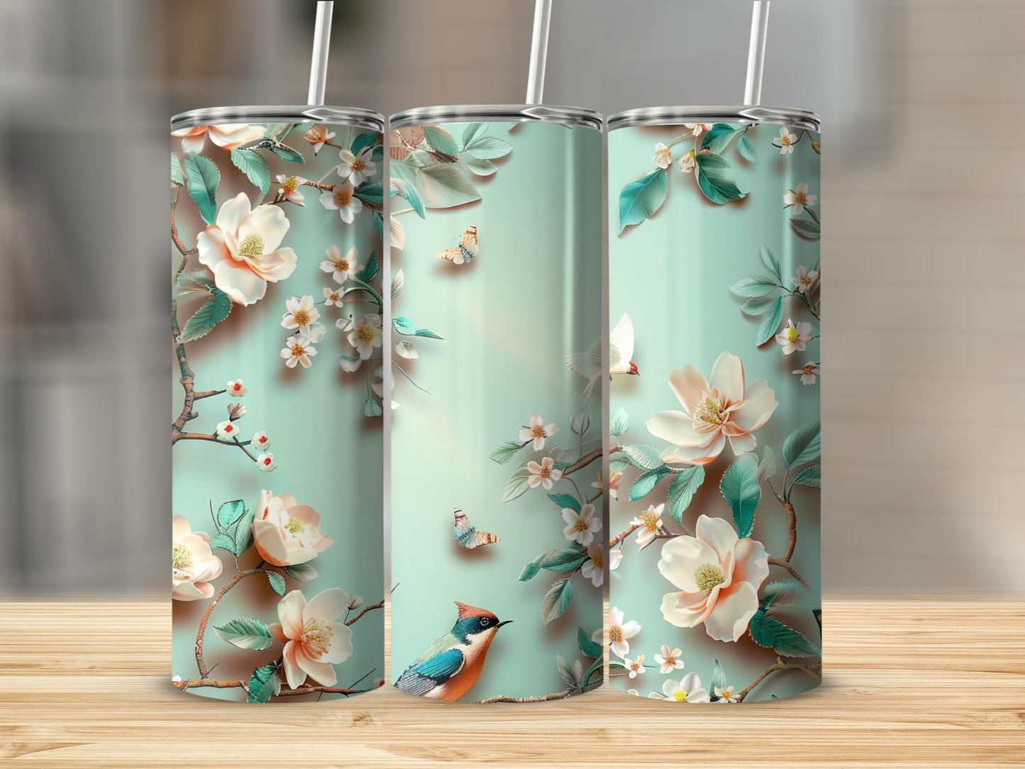 Three tall tumblers with a floral and bird design on a wooden surface.