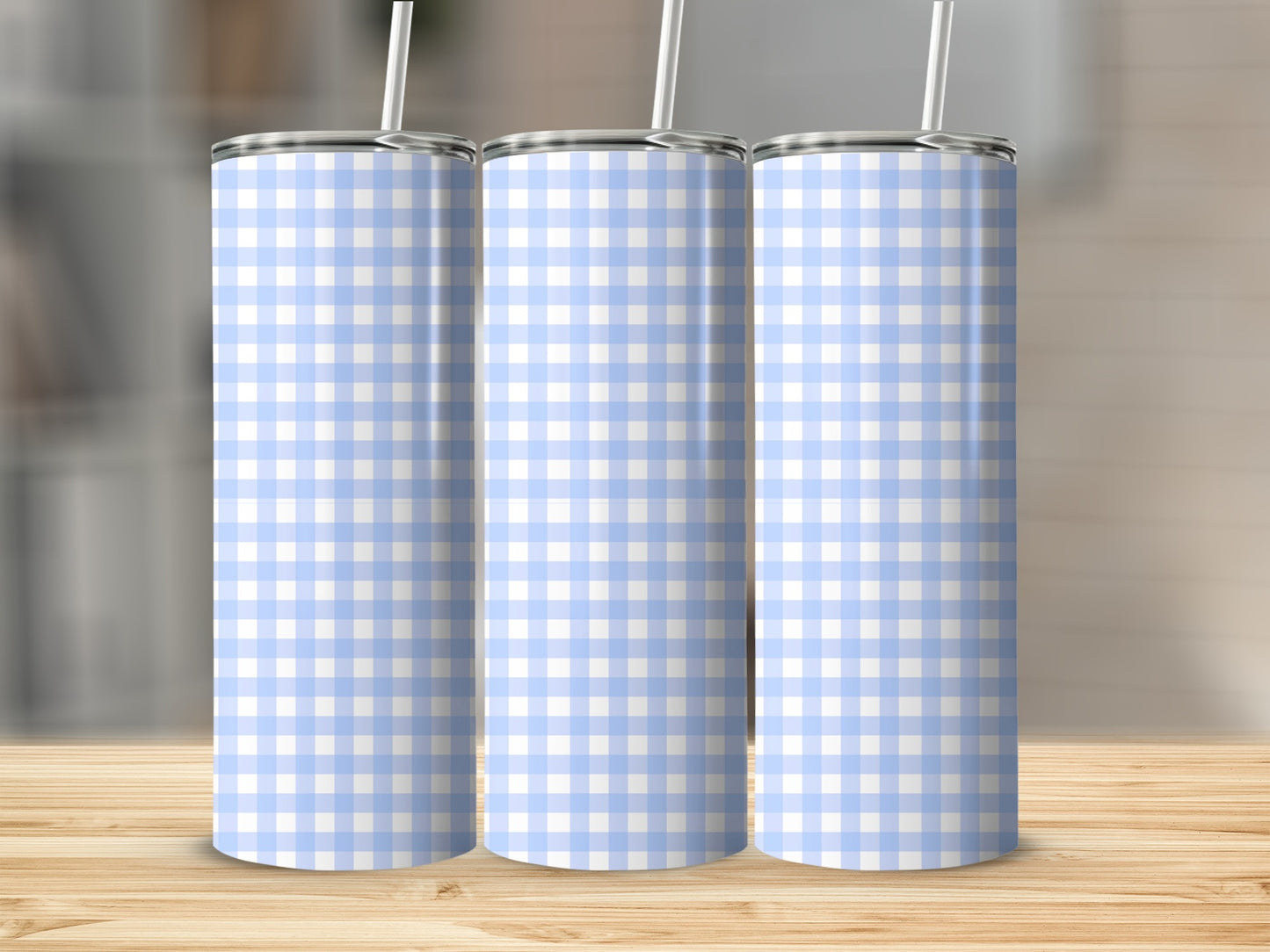Three blue and white checkered tumblers with straws on a wooden surface.