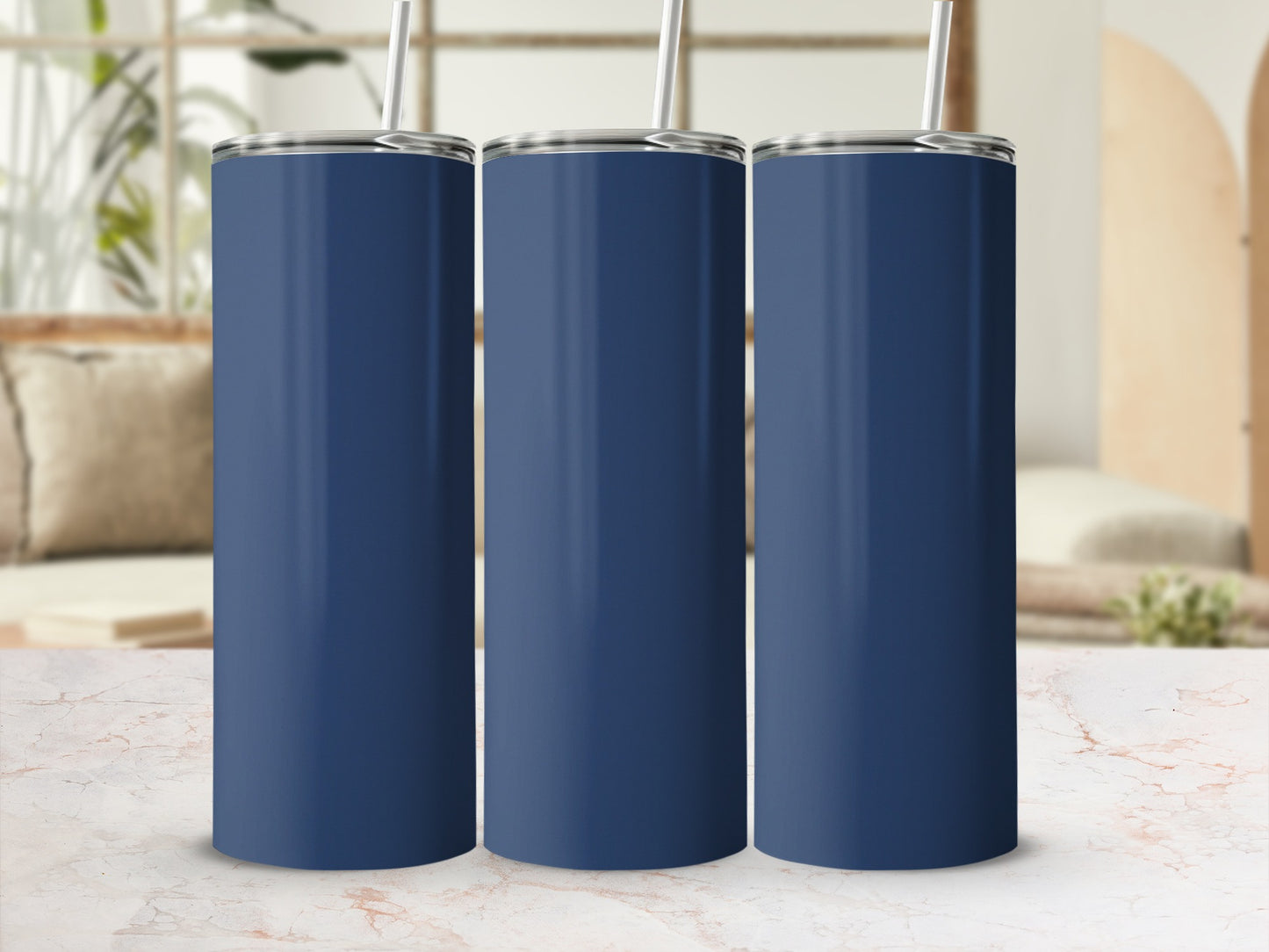 Three navy blue tumblers with straws in a row on a marble surface.