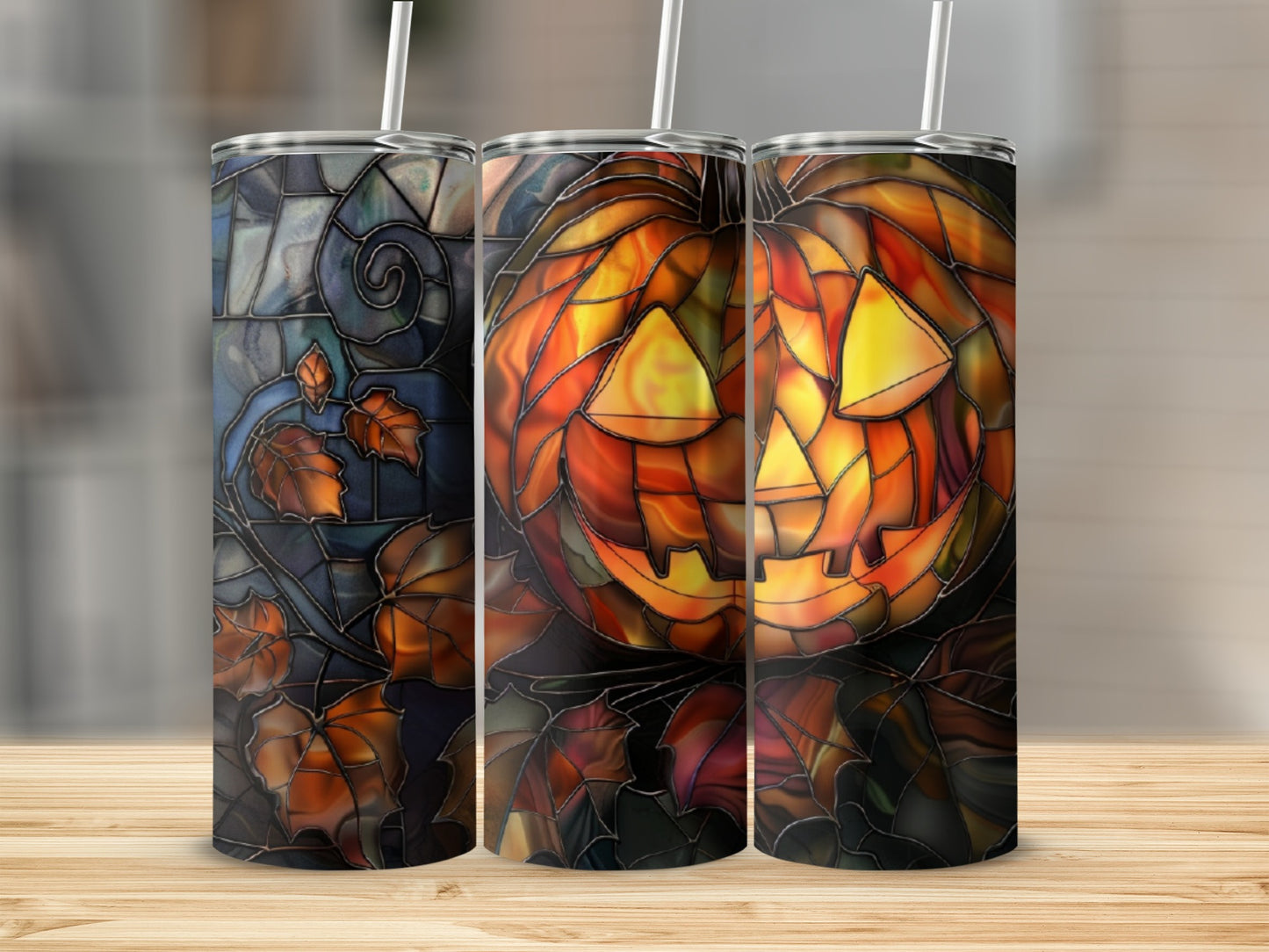 Three tumblers with stained-glass Halloween designs: jack-o'-lantern and fall leaves.