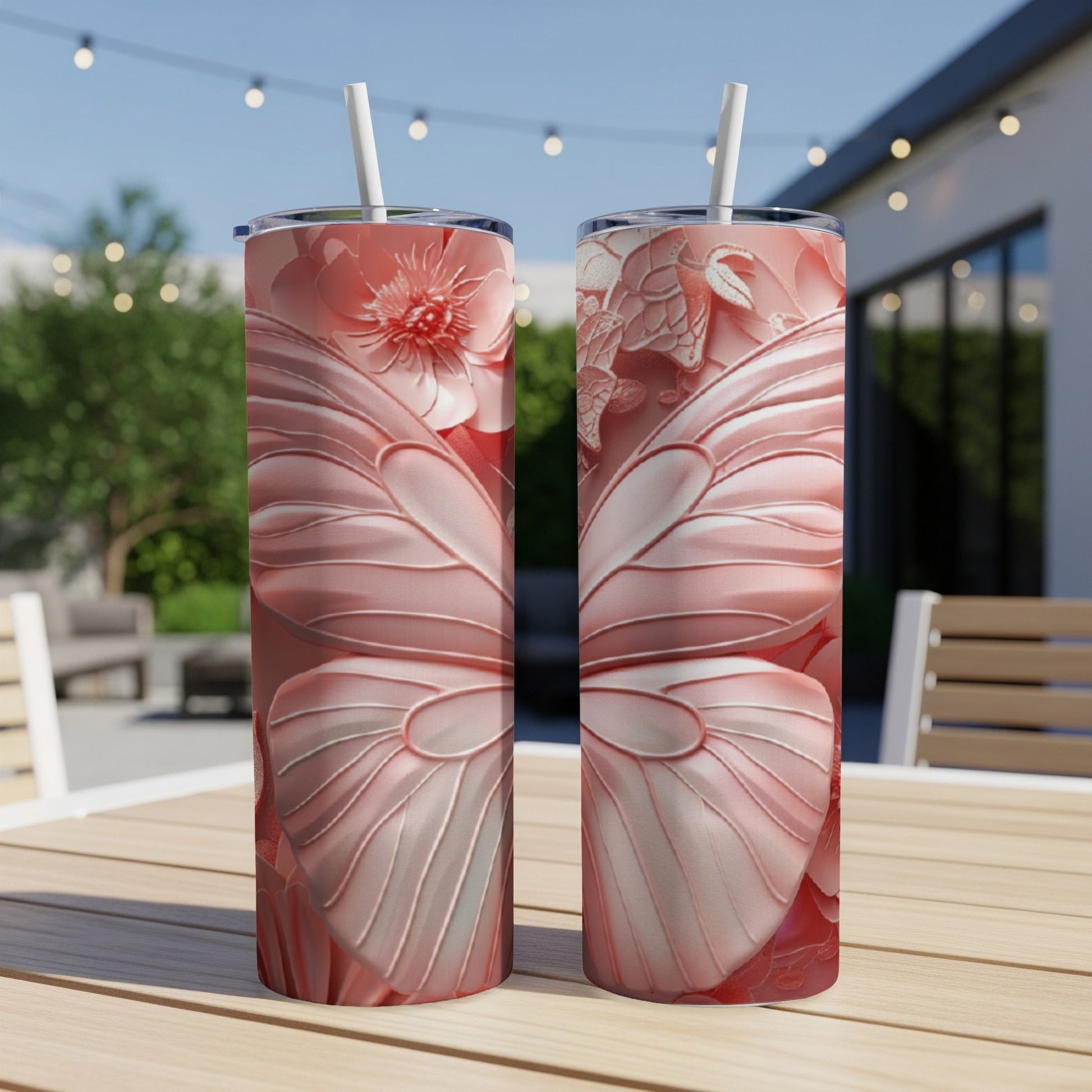 Two pink floral butterfly tumblers on a wooden table outdoors.
