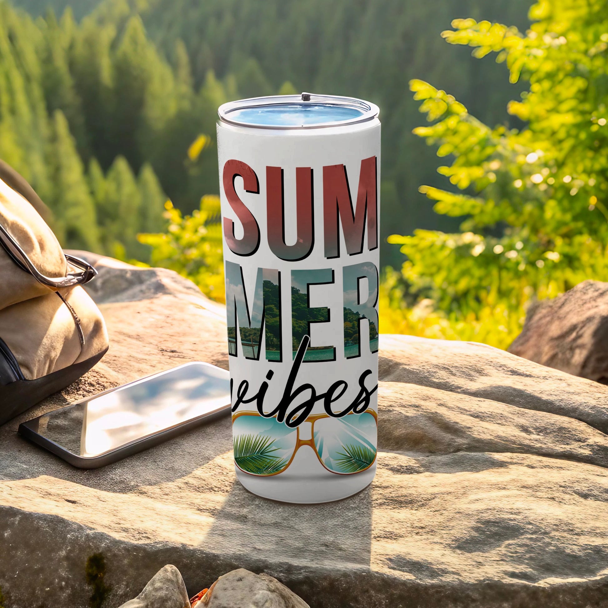 Tumbler with "SUMMER VIBES" and sunglasses design outdoors.