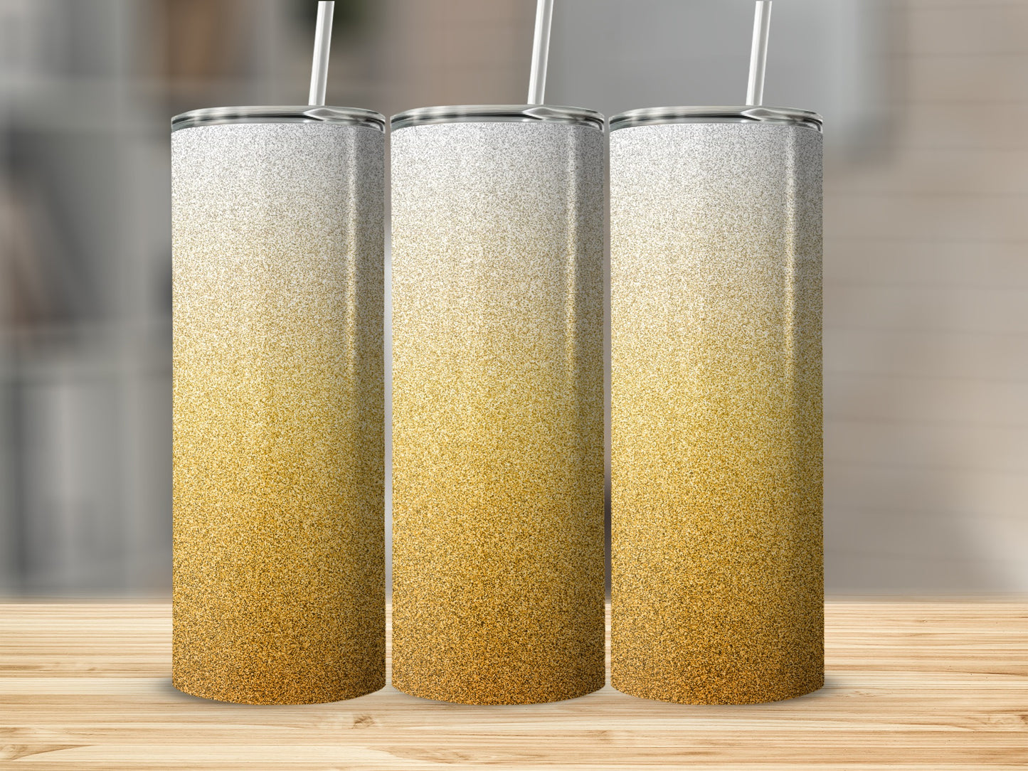 Three tall tumblers with gold glitter ombre design on a wooden surface.
