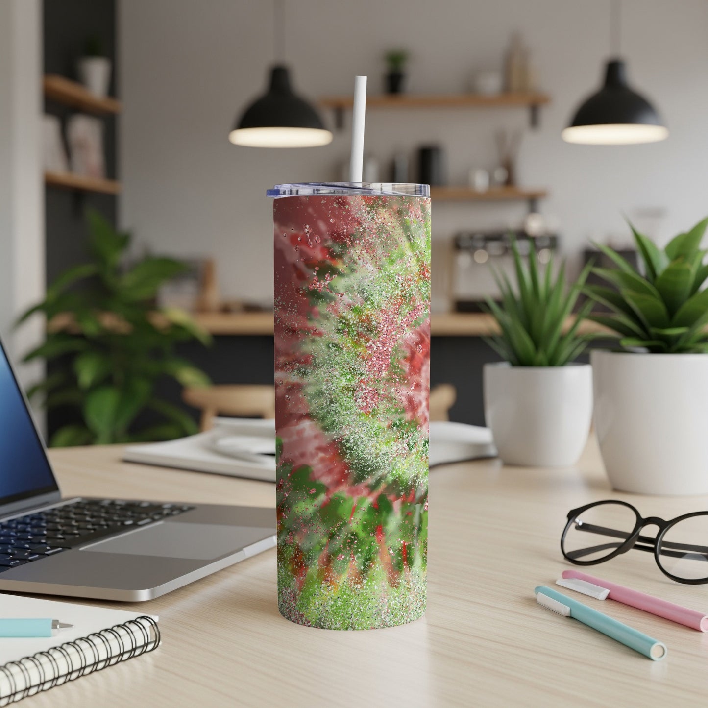 Glittery red and green abstract pattern on a stainless steel tumbler with a straw.