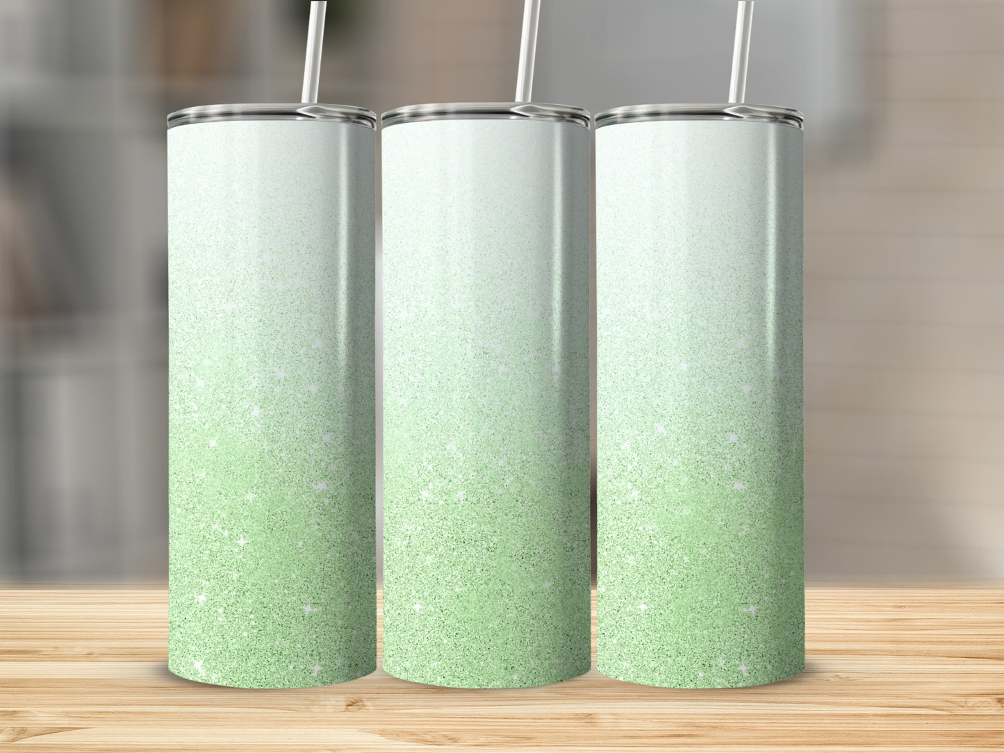 Three glitter tumblers with green and white ombre gradient, on a wooden surface.