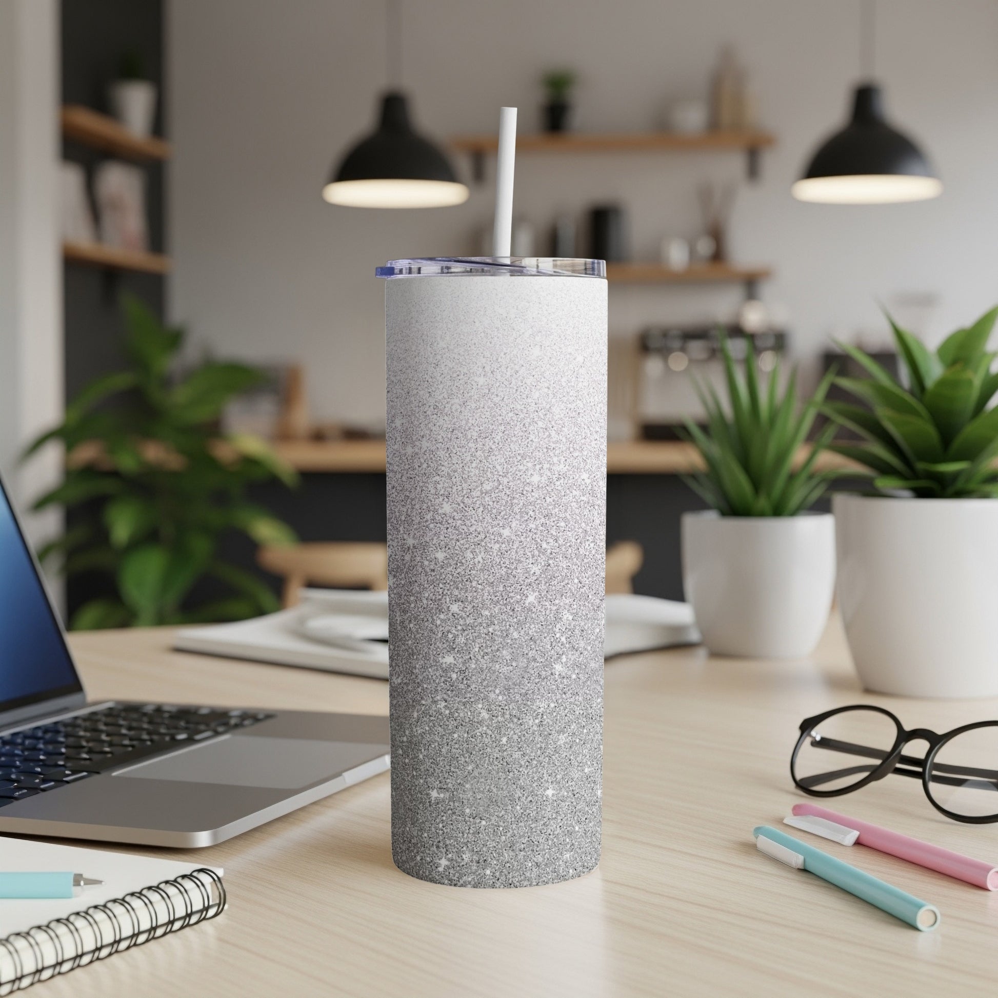 Silver glitter ombre stainless steel tumbler with straw on desk.