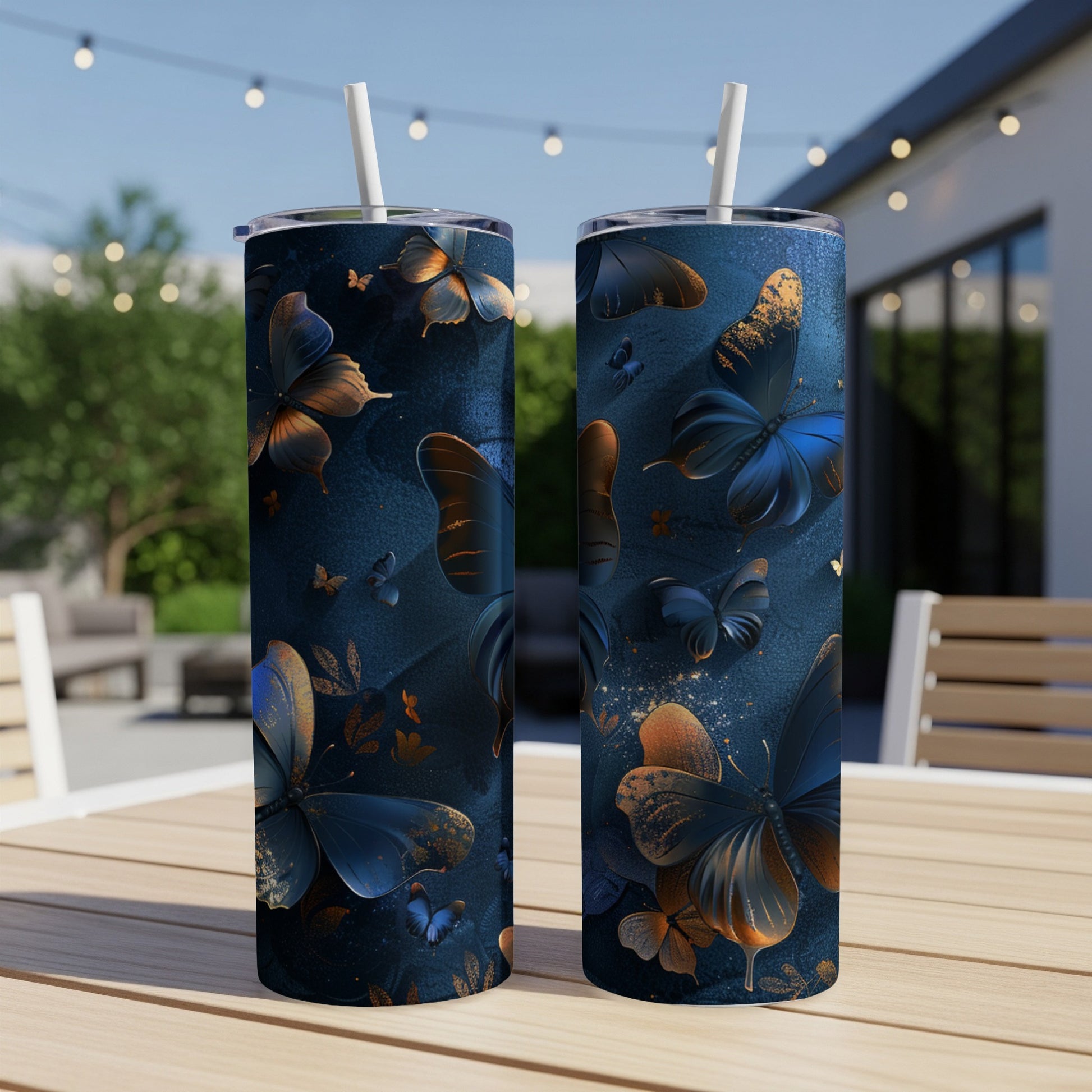 Two blue tumblers with golden butterfly designs on a wooden table.