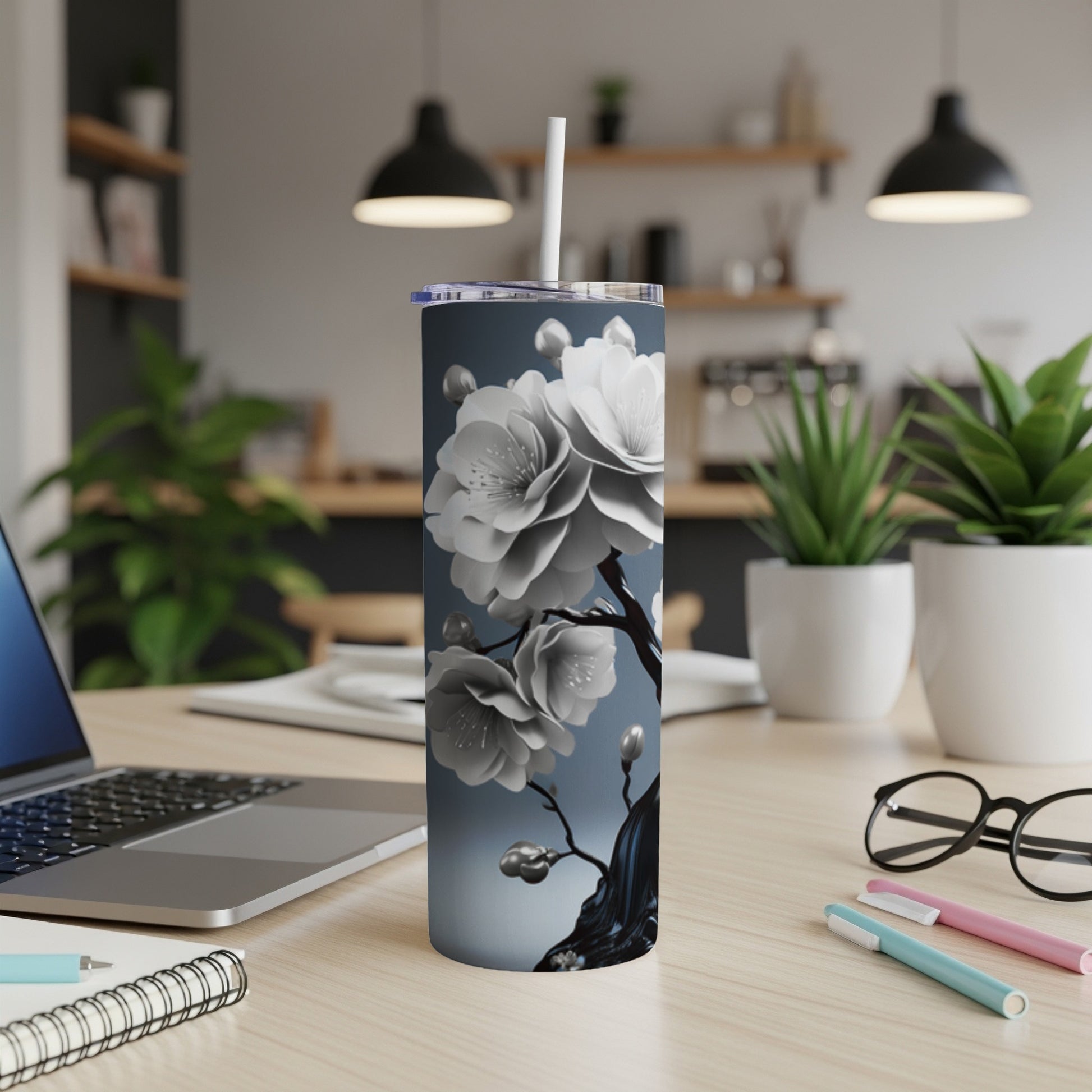 Silver tumbler with white cherry blossoms on a dark background.