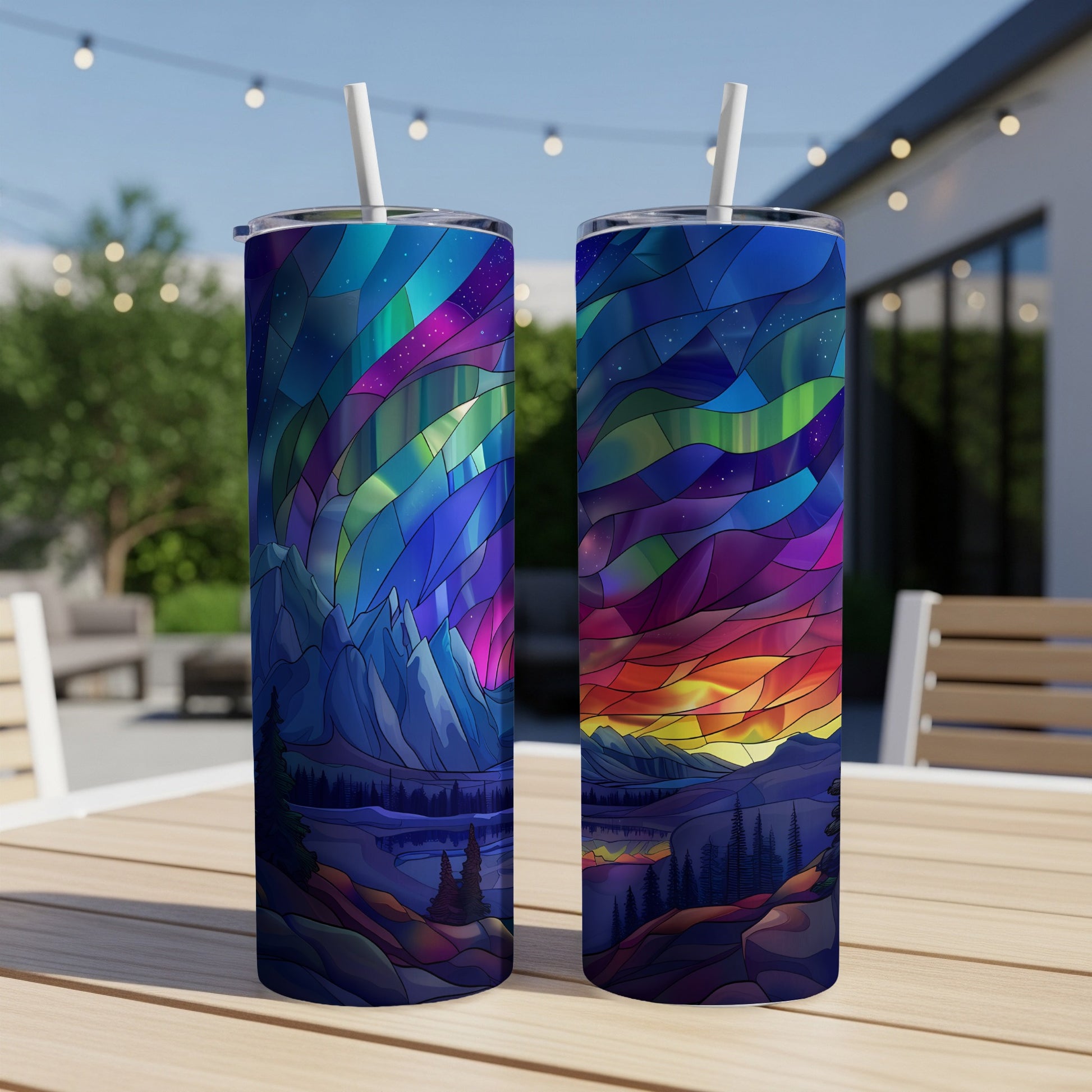 Two tumblers with stained-glass aurora borealis design on wooden table outdoors.