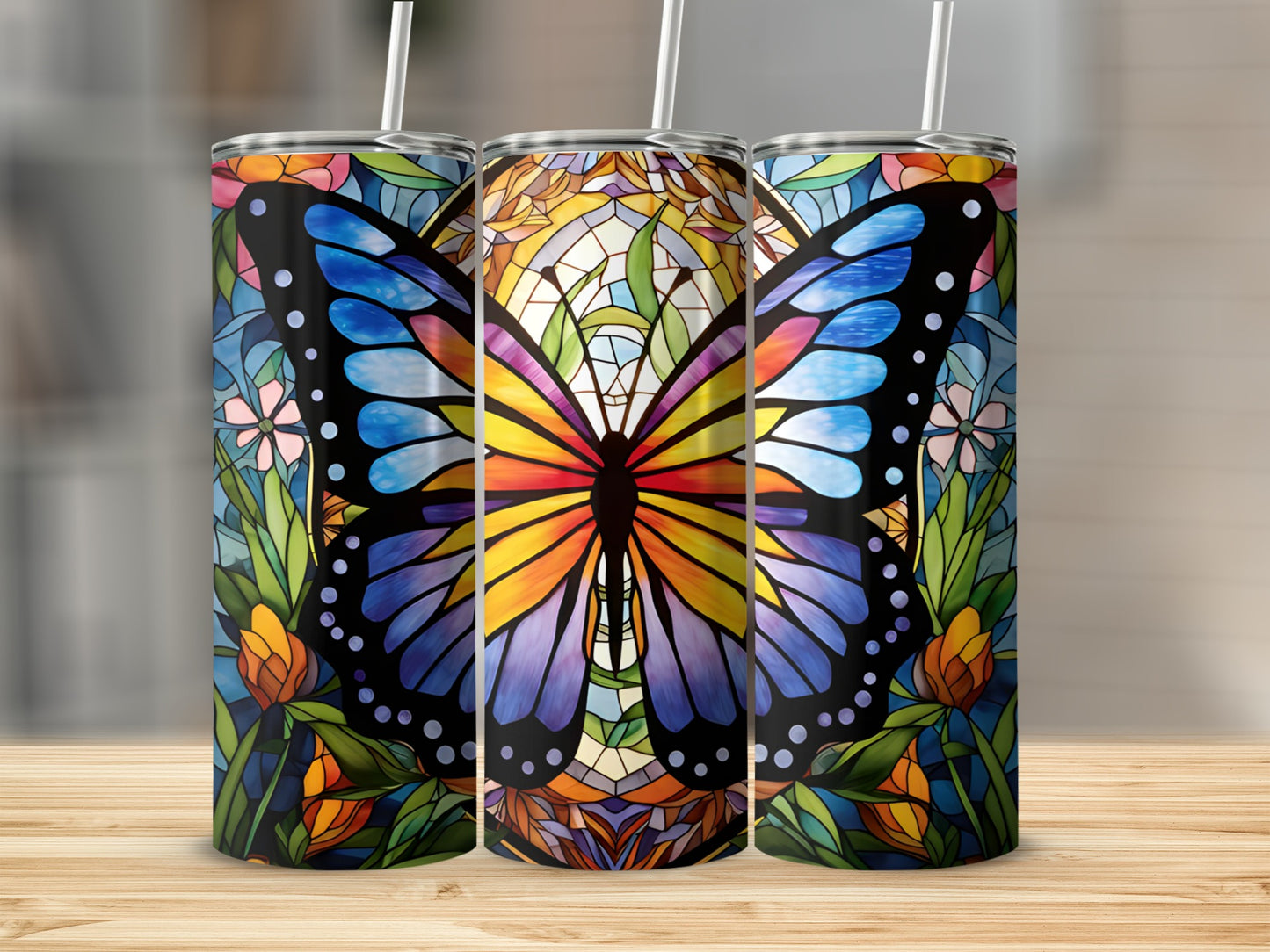 Three tumblers with stained-glass butterfly and floral designs on a wooden surface.