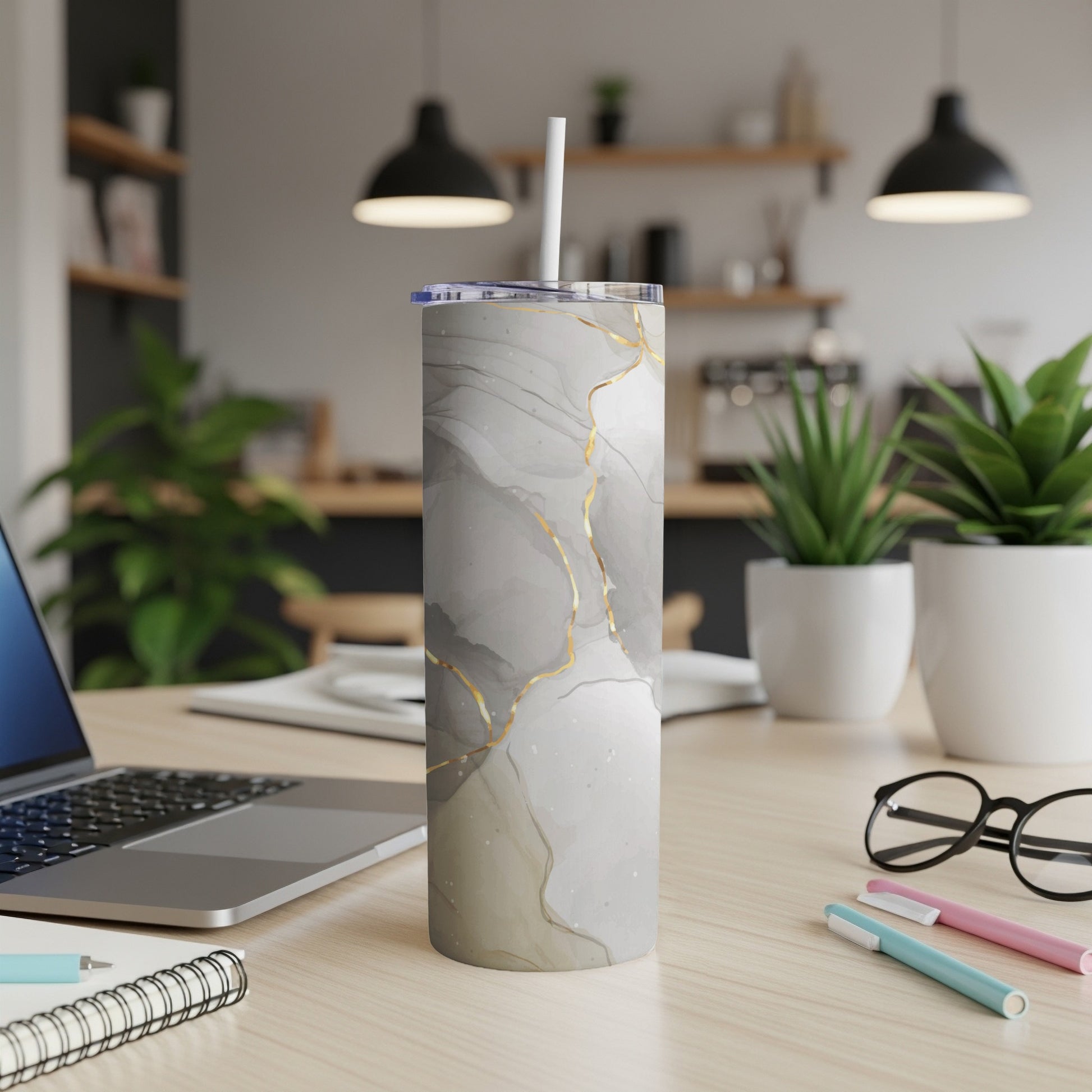 Marble-patterned tumbler with gold accents and a straw on a desk.