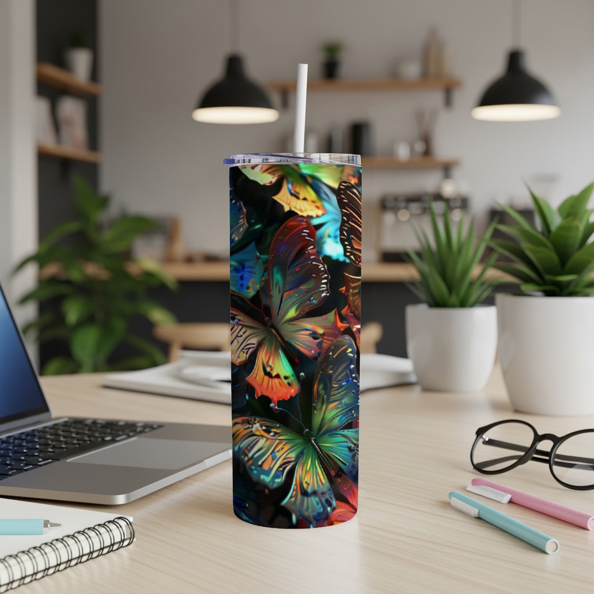 Tall tumbler with colorful butterfly pattern and straw on a desk.